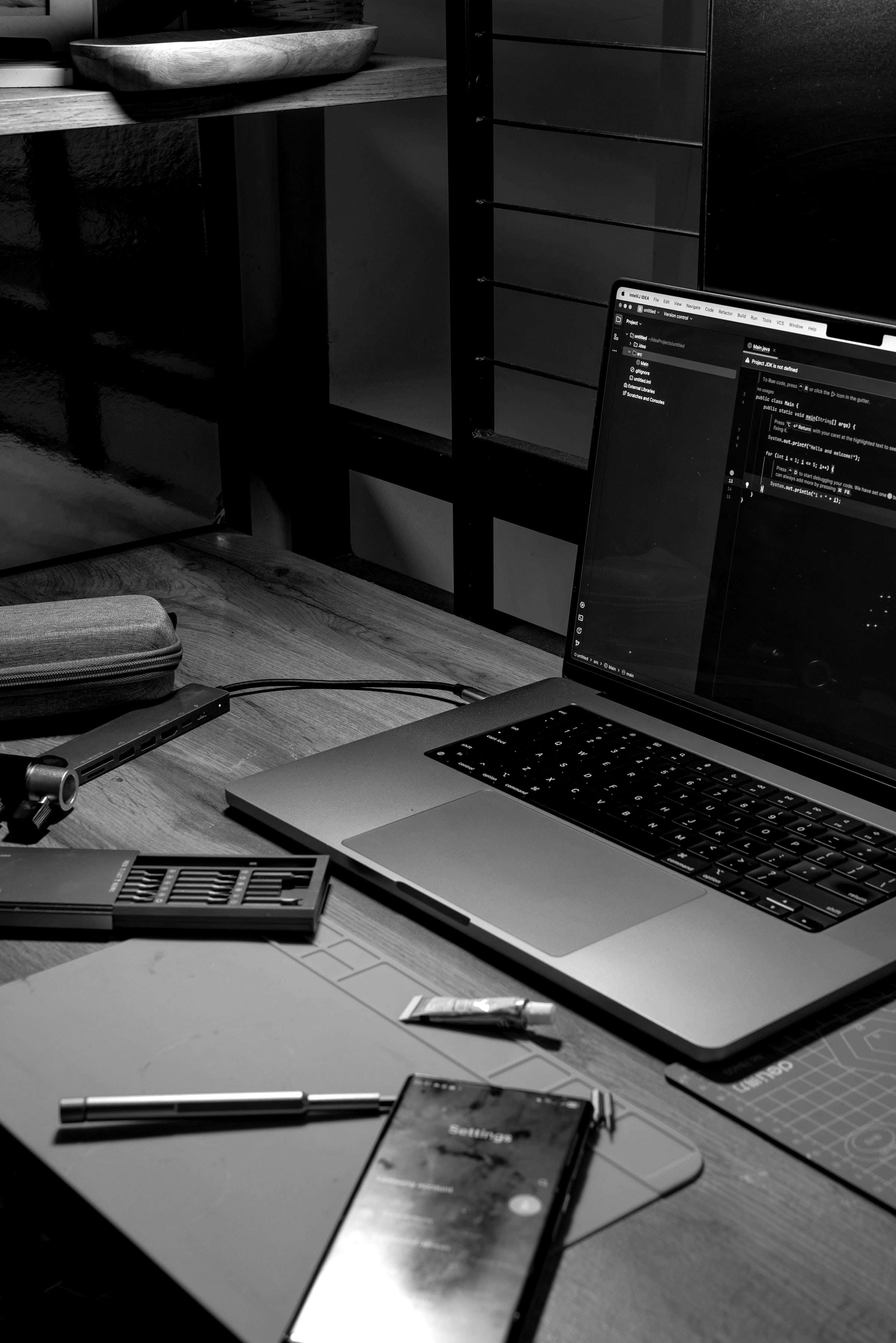 Portátil con código en pantalla sobre una mesa de trabajo, junto a un móvil.